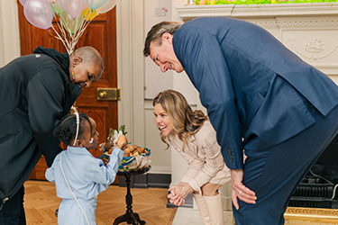 The First Lady and Governor bend down to greet a young girl holding an Easter egg inside the Mansion.