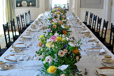 Dining table set with a white table cloth and flowers running down the length of the table.